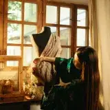A fashion designer drapes elegant fabric on a mannequin, showcasing creativity and craftsmanship in tailoring.