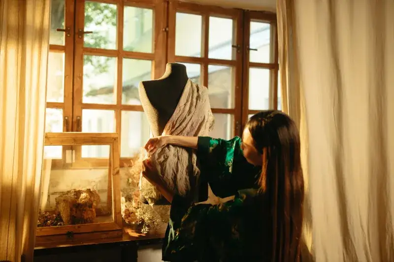 A fashion designer drapes elegant fabric on a mannequin, showcasing creativity and craftsmanship in tailoring.
