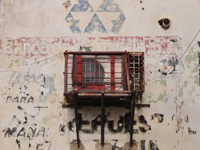 Weathered wall with air conditioner in Maracaibo, showcasing urban decay and street art.