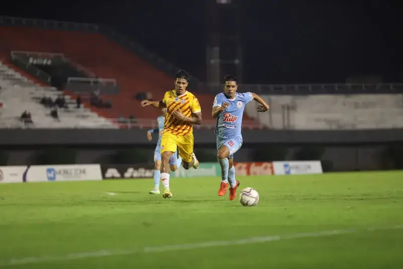 Dynamic capture of two soccer players competing on the field at night, showcasing athleticism and teamwork.