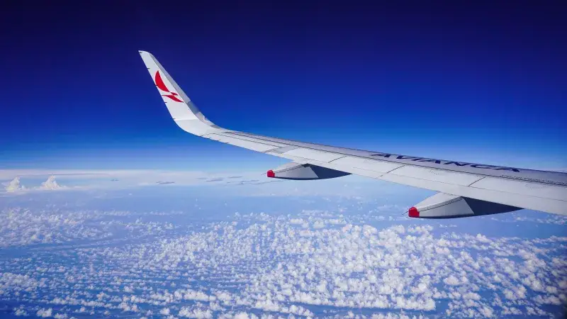 Stunning aerial view of an Avianca airplane wing above clouds during flight over Colombia.