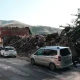 A city street with cars passing by buildings destroyed by an earthquake.
