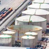 Aerial shot of large oil storage tanks in an industrial district with adjacent railway tracks.