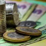 Imagen de primer plano de monedas apiladas y varias notas de moneda, representando conceptos financieros.