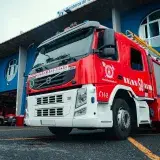 A modern fire truck parked outside a blue urban fire station, ready for emergency response.