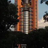 Modern tower in Maracay, Venezuela framed by trees during sunset, creating a striking urban scene.