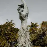 Vertical shot of a Holocaust memorial statue in Miami park surrounded by lush greenery.
