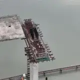 Aerial view of an unfinished bridge structure over water, showcasing construction progress.