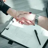 Close-up of a professional handshake over a contract, symbolizing a successful business deal.