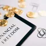 Close-up of Bitcoin coins and an iPad displaying 'Financial Freedom,' symbolizing modern digital savings.