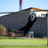 Goalkeeper makes a dramatic save during an outdoor soccer match.