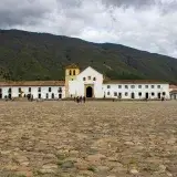 Cobblestone square of Villa de Leyva, Colombia with colonial architecture and mountain backdrop.