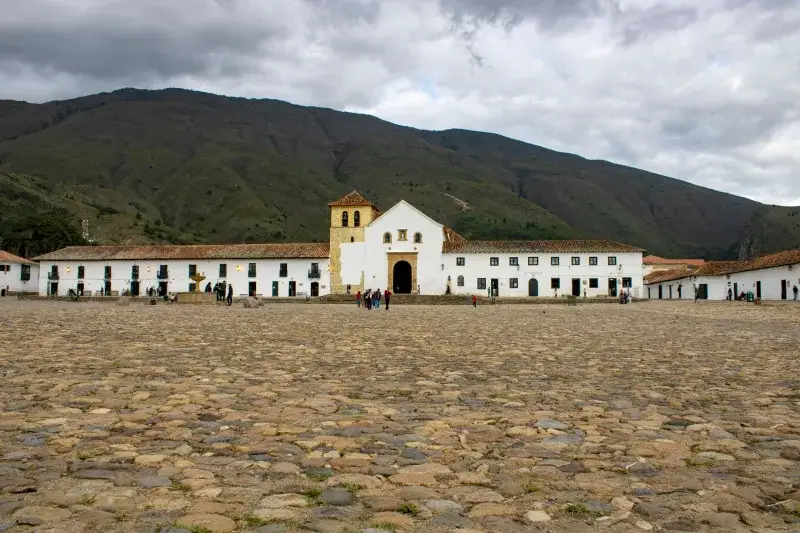 Cobblestone square of Villa de Leyva, Colombia with colonial architecture and mountain backdrop.