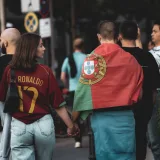 A group of football fans in Berlin, one wearing a Portugal flag, walking the street.