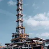 Vertical shot of an oil refinery tower in Trzebinia, Poland against a clear sky.