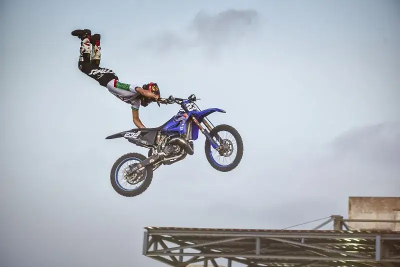 Motorcyclist performs an aerial trick on a blue bike in Rabat, Morocco.