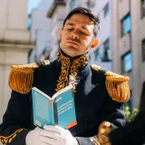Man in period costume reading a book outdoors in Buenos Aires, Argentina, evoking a historical theme.