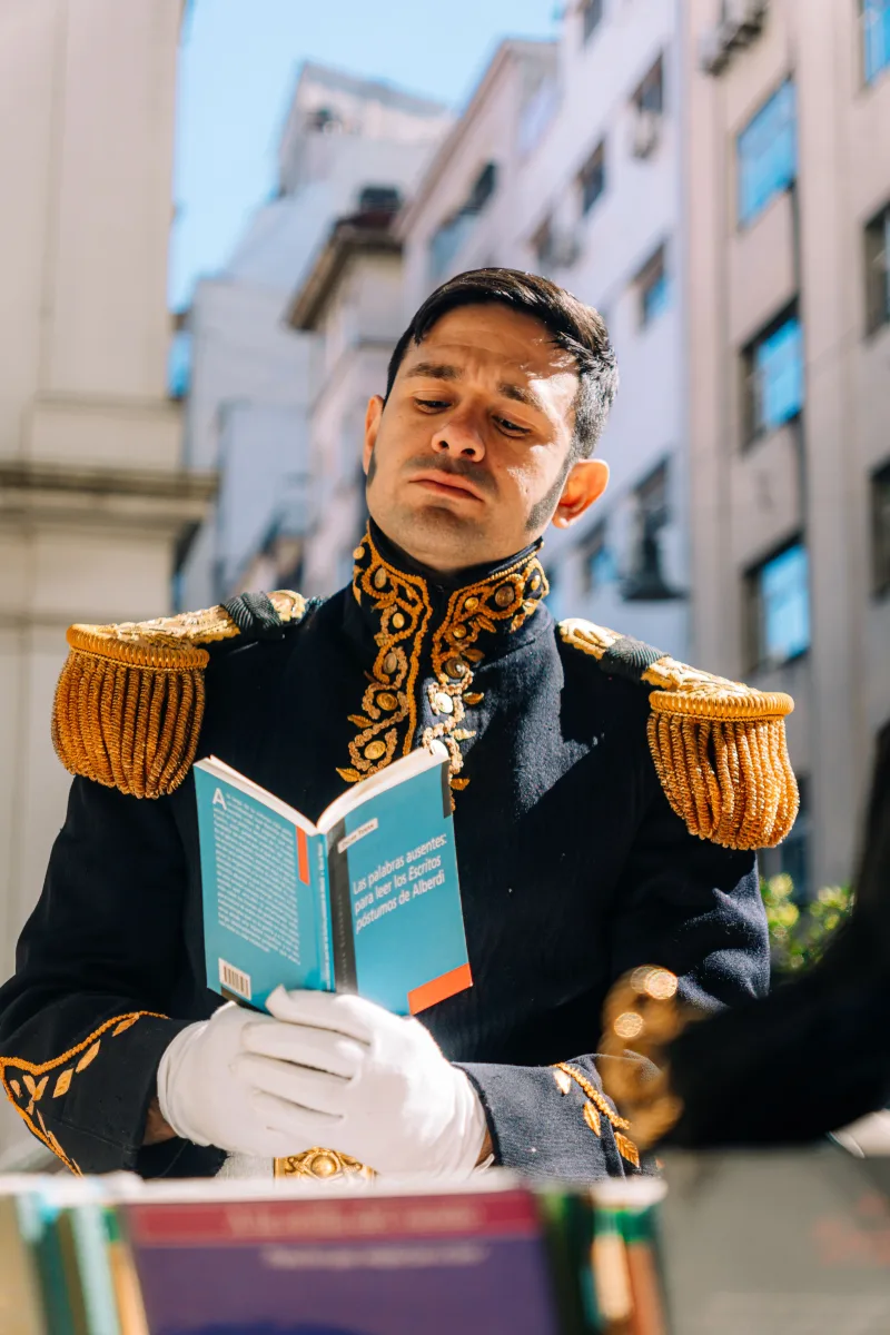 Man in period costume reading a book outdoors in Buenos Aires, Argentina, evoking a historical theme.