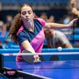 A female athlete intensely focused during a competitive table tennis match, showcasing skill and determination.