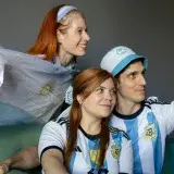Fans wearing Argentina jerseys cheer while watching a match indoors. Captured in Buenos Aires.