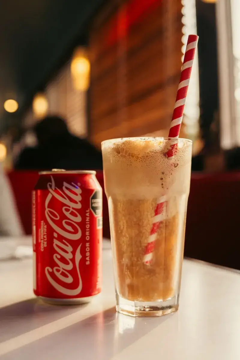 A chilled Coca-Cola float with a striped straw in a cozy Buenos Aires cafe, capturing an authentic dining experience.