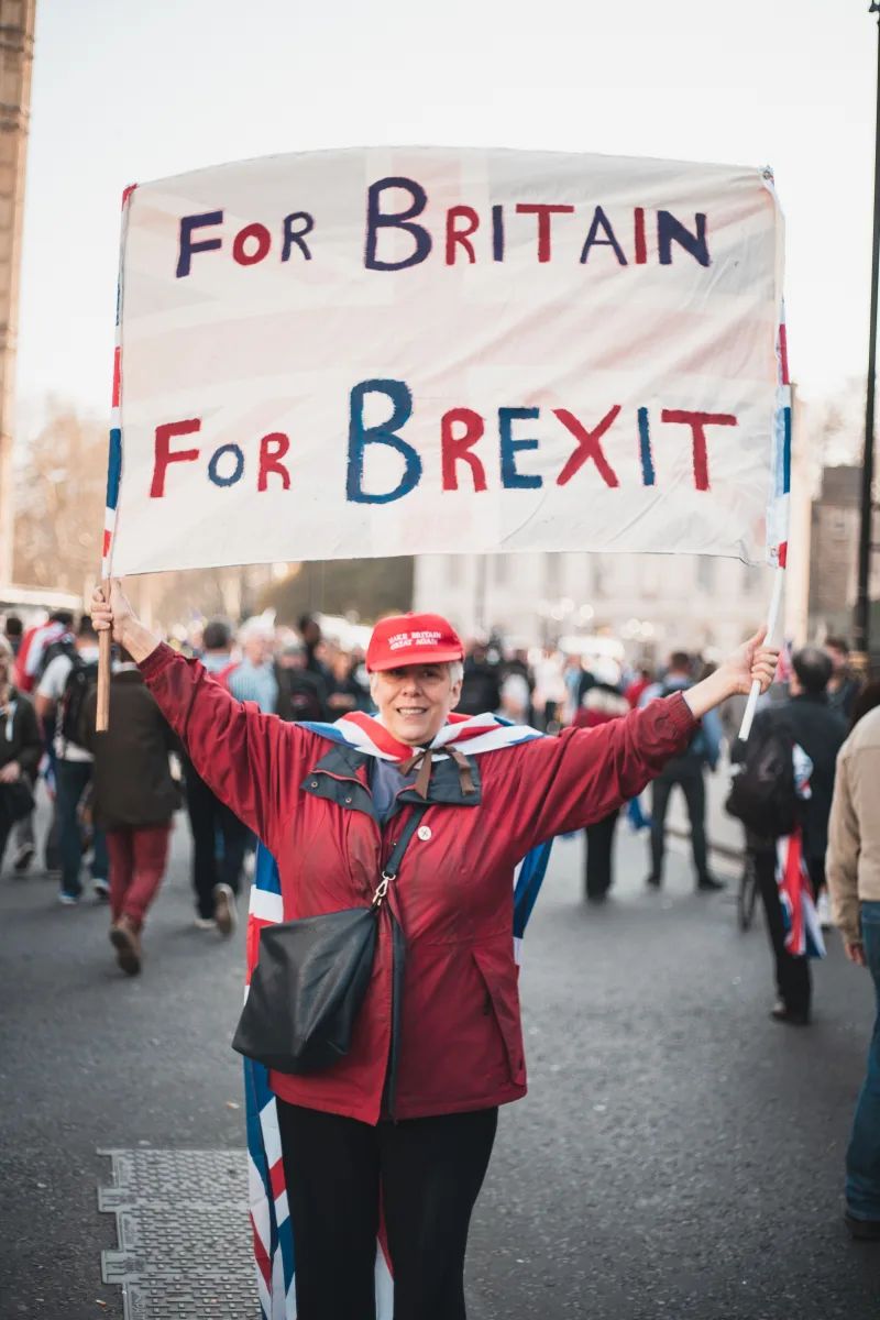 Woman in red jacket holding a 'For Britain For Brexit' sign during a protest in London.