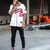 African American man posing stylishly in Atlanta Braves jersey at a construction site. Urban fashion captured outdoors.
