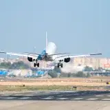 An airplane lands on a sunny day at Manises Airport, Valencia, showcasing aviation in action.