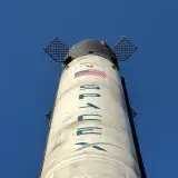 Close-up view of a SpaceX rocket against a clear blue sky, showcasing its structure and design.
