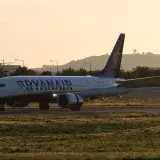 Ryanair Boeing 737 airplane lands on runway during sunset.