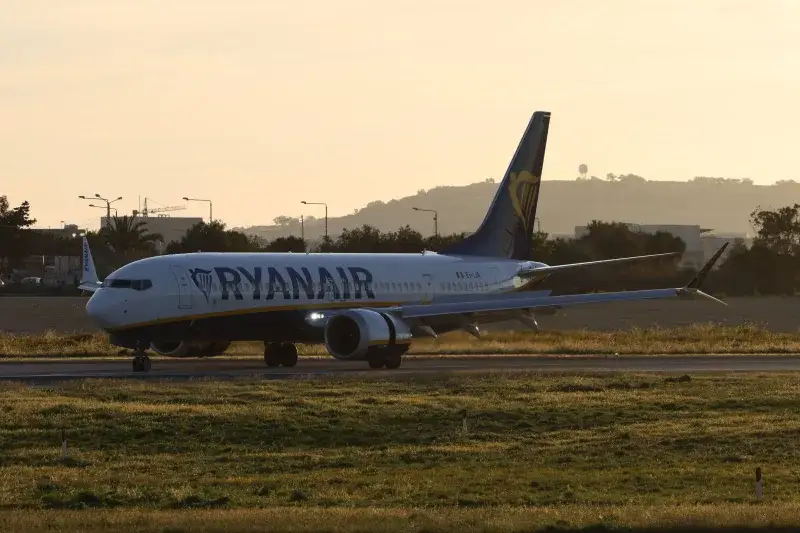 Ryanair Boeing 737 airplane lands on runway during sunset.
