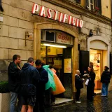 People gather outside Pastificio Guerra in Italy, enjoying an urban street scene.