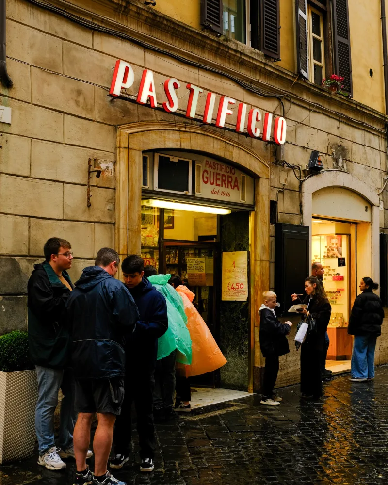 People gather outside Pastificio Guerra in Italy, enjoying an urban street scene.