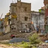 A detailed view of urban decay and reconstruction efforts in Puri, India, showcasing damaged buildings and workers.
