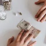 From above patient with money and pills sitting at table with laptop and notebook while deal purchasing medicine in clinic