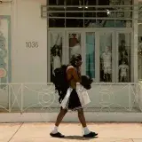 Man walking past a Miami boutique carrying shopping bags in the summer sun.