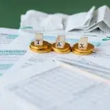 Close-up of tax forms, receipts, and coins symbolizing financial accounting and taxes.