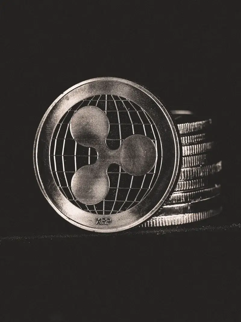 Monochrome image of Ripple coins stacked vertically, symbolizing digital currency.