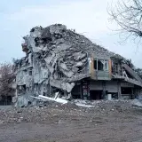 Collapsed building in urban landscape showing earthquake devastation and debris.