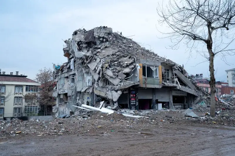 Collapsed building in urban landscape showing earthquake devastation and debris.