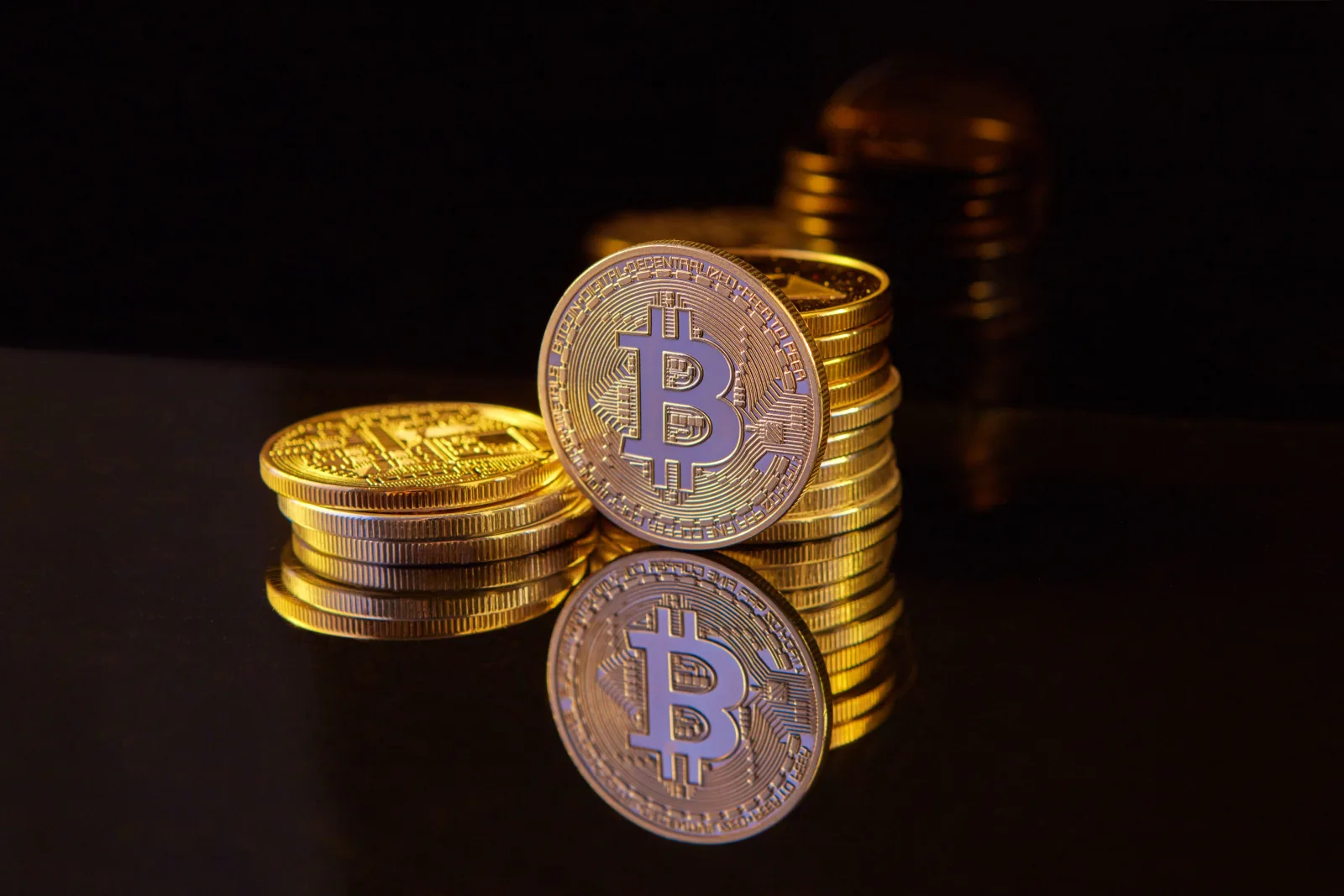 Close-up image of Bitcoin stacks on a reflective surface symbolizing digital currency and wealth.
