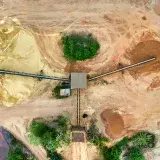 Aerial shot of a mining site featuring conveyor belts and sand piles.