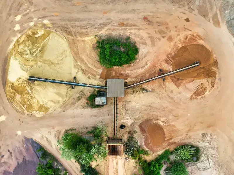 Aerial shot of a mining site featuring conveyor belts and sand piles.