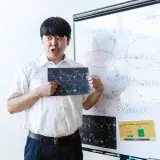 A man presenting cryptocurrency concepts on a whiteboard with charts and graphs.