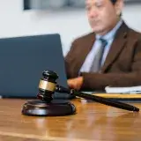 Crop concentrated Asian male judge in formal clothes sitting using modern netbook while working in law office