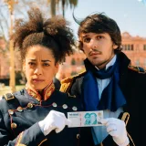 Historical reenactors in Buenos Aires costumes holding a banknote in front of Casa Rosada.