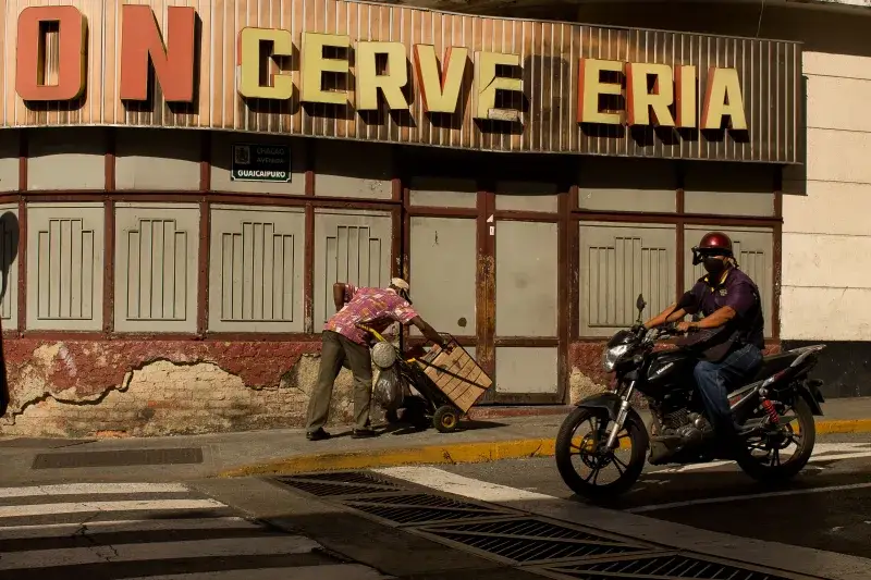 Un momento en Caracas que muestra la vida urbana con un motociclista y un vendedor ambulante.