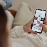 Person using smartphone to browse Instagram indoors, showing social media engagement.