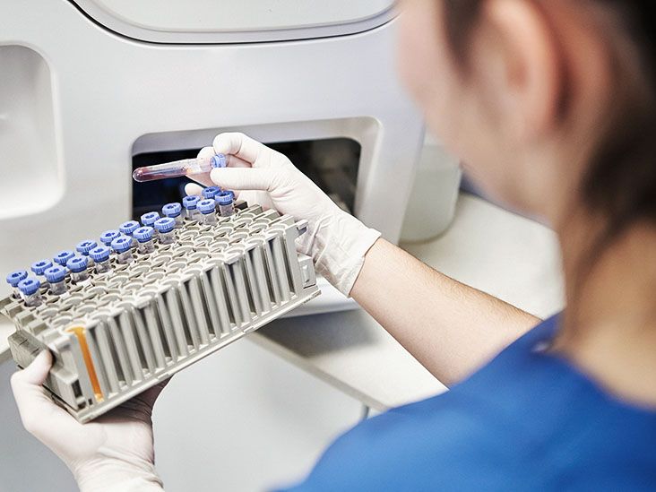 A medical professional examines a tray of blood vials