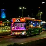 Brightly lit bus on Buenos Aires city street at night, showcasing urban transport.
